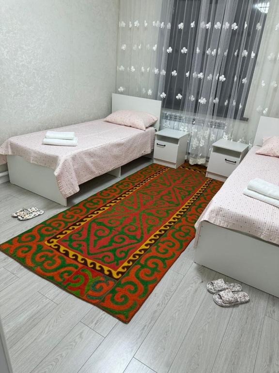 a bedroom with two beds and a rug at Rest House in Bokonbayevo