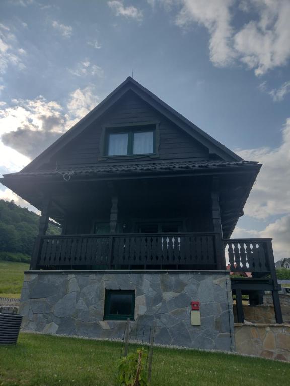 a house with a roof on top of a field at Domki BIERWIONO in Cisna