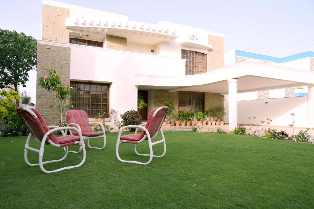 a group of chairs sitting on a lawn in front of a house at Elevé Stays - Boutique Family Suites in Karachi