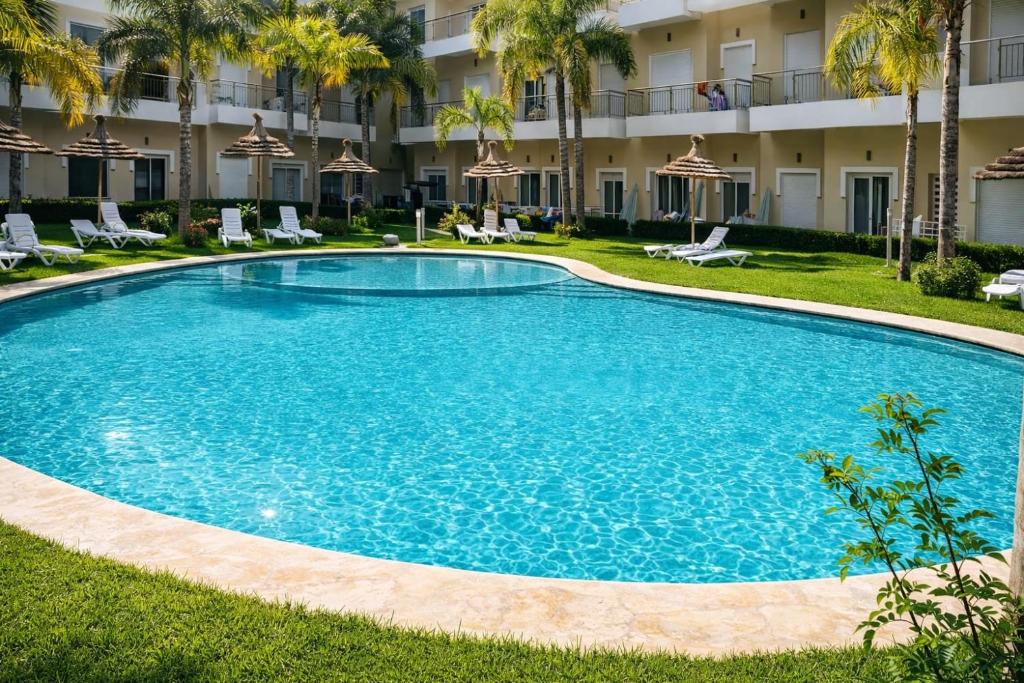 a large swimming pool in front of a hotel at Cosy appartement in Bouznika