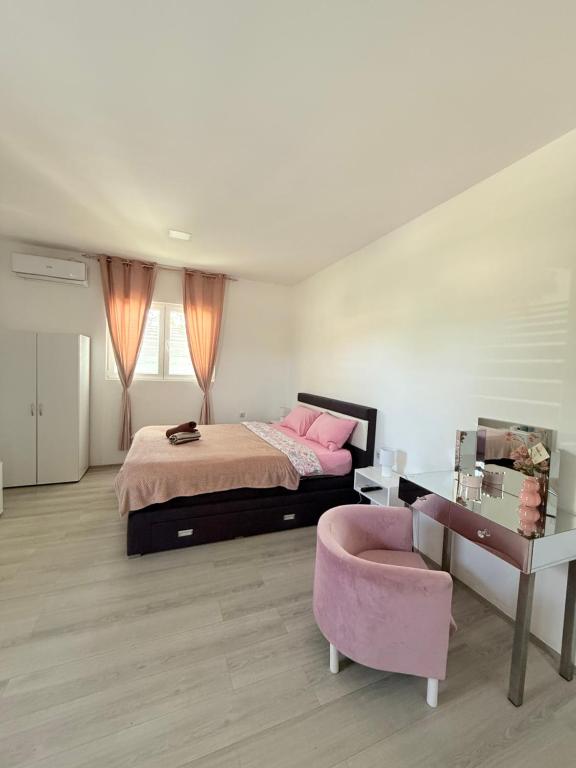 a bedroom with a bed and a pink chair at Apartmani Home in Zaječar