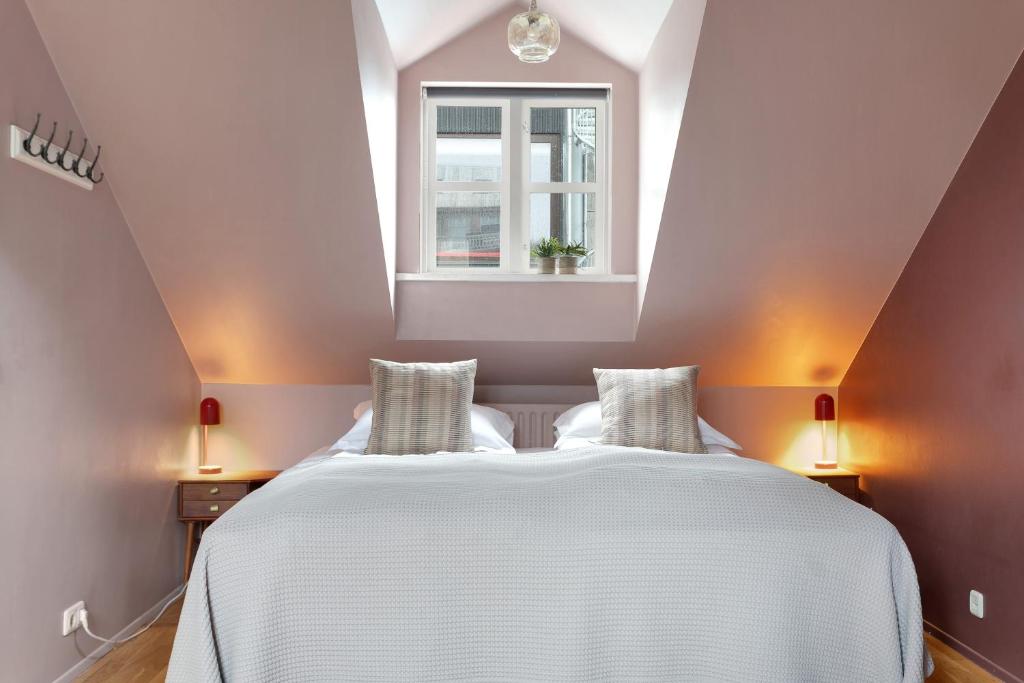 a bedroom with a white bed and a window at Grettir Guesthouse Downtown Charm in Reykjavík
