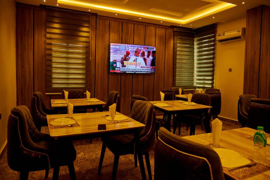 a dining room with tables and chairs and a tv at Motion Hotel and Suites, Uyo in Uyo