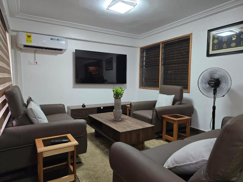 a living room with couches and a table and a fan at Green Life Apartment in Sakumona
