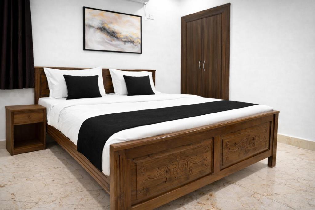 a bedroom with a large wooden bed with black and white pillows at Hotel CJ Grand Vijayawada in Vijayawāda