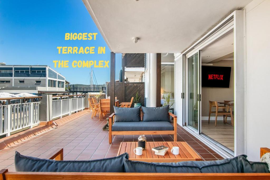 a patio with a couch and a table on a balcony at Knysna Waterfront, Stunning Views in Knysna