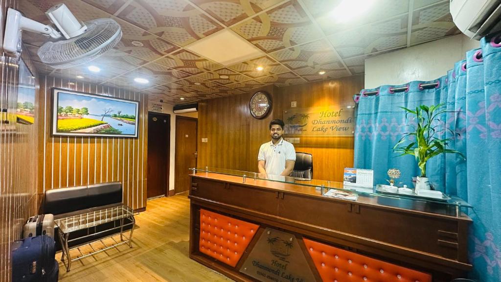 a man standing behind a counter in a restaurant at Dhanmondi Lake View Hotel in Dhaka