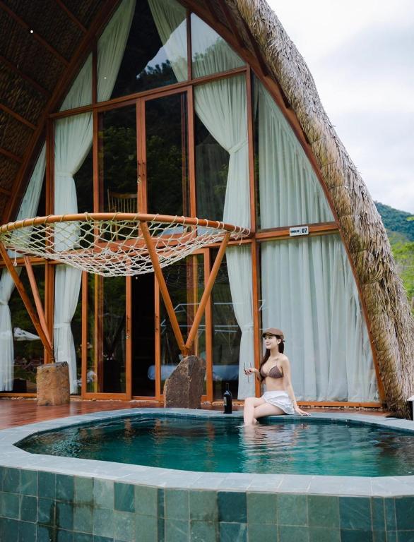 a woman sitting in the water in a swimming pool at Leaf Village & Farm Làng Lá in Danang