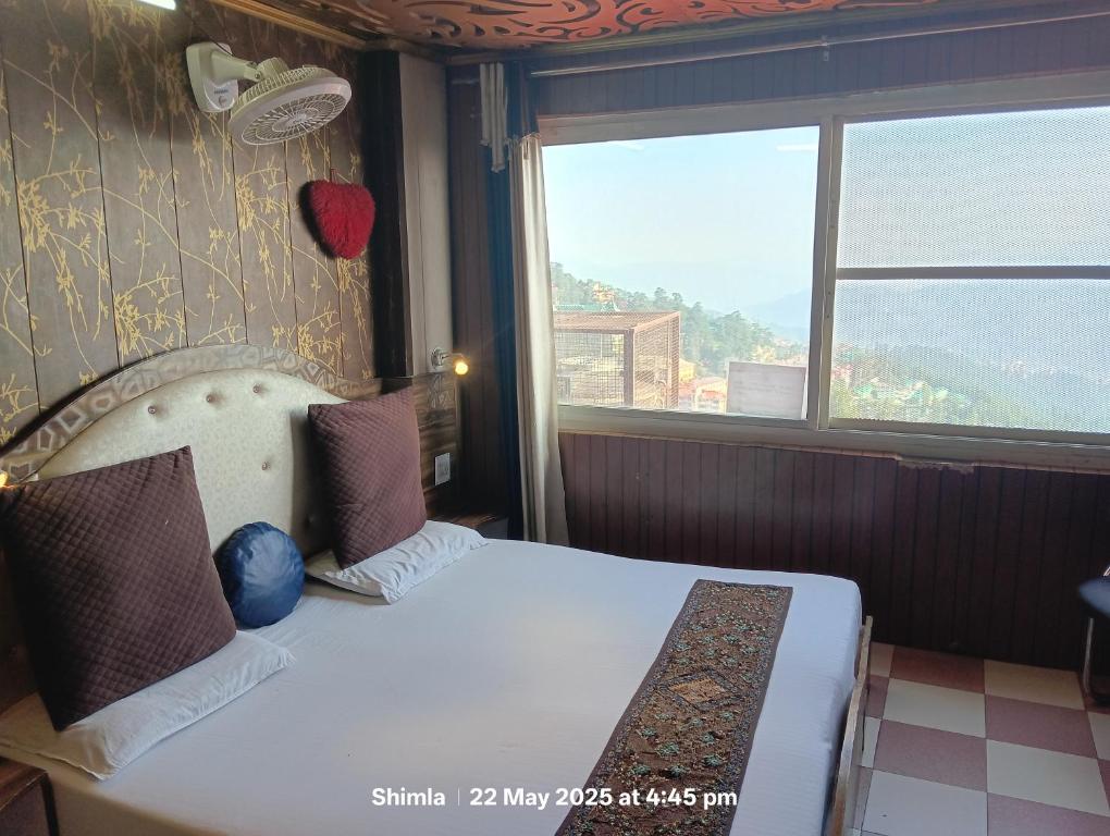 a bedroom with a bed and a large window at New Malook hotel in Shimla