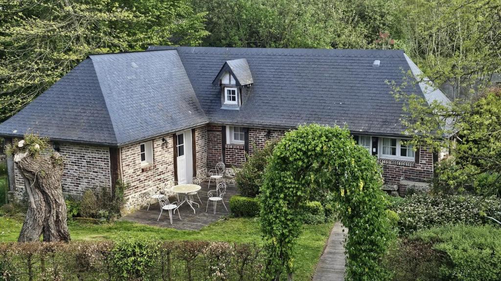 a small brick house with a table and chairs at Gîte les deux saules in Yquebeuf