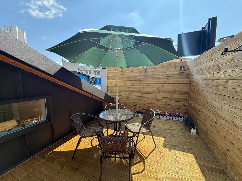 a table and chairs with an umbrella on a patio at GreeneStay Sindang DDP Seoul in Seoul