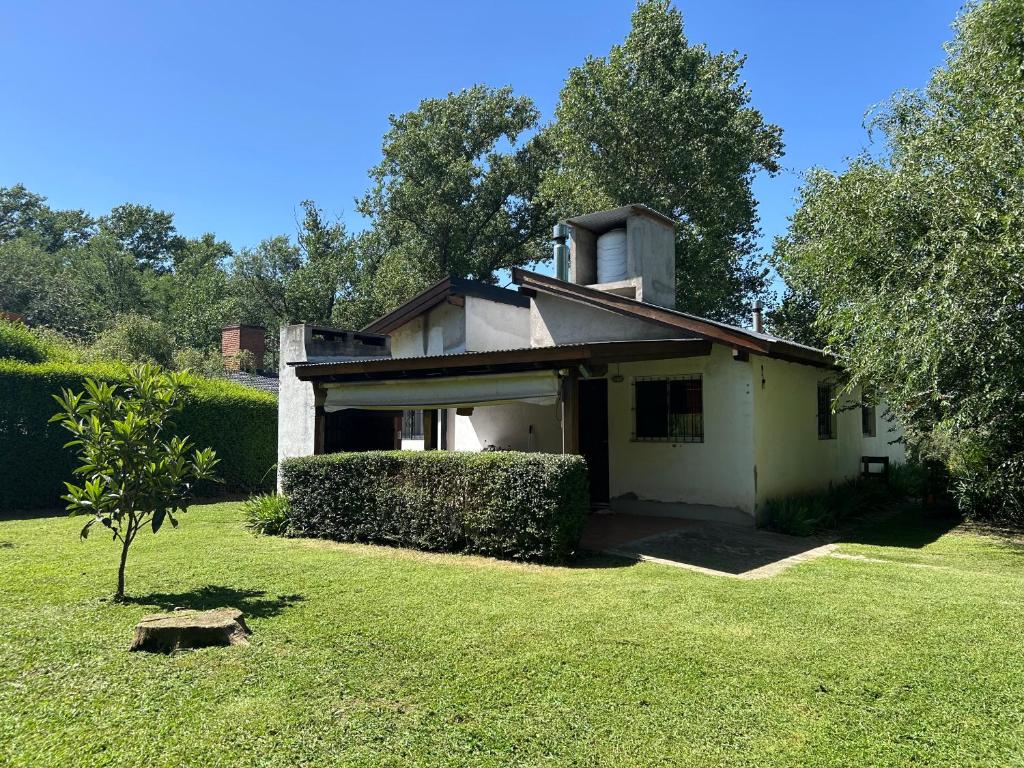 a small white house with a grass yard at Los Manzanos in Villa Ciudad Parque