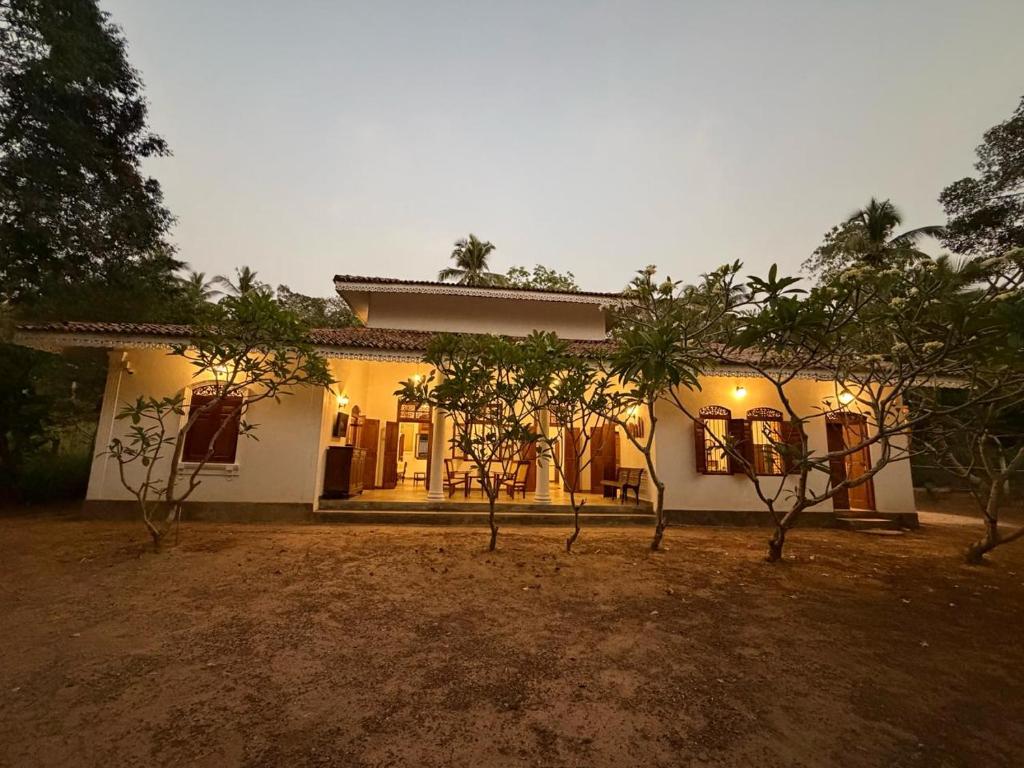 a white house with trees in front of it at The Surveyor's Bungalow in Udugampola
