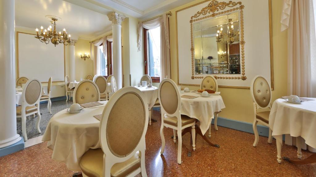a dining room with tables and chairs and a mirror at Hotel Arlecchino in Venice