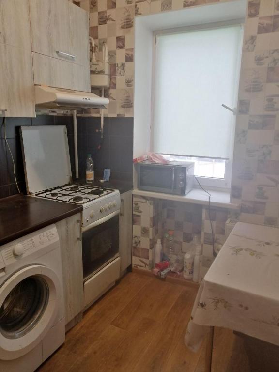 a kitchen with a stove and a washing machine at Квартира in Sumy