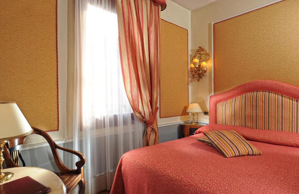 a bedroom with a red bed and a window at Hotel Arlecchino in Venice