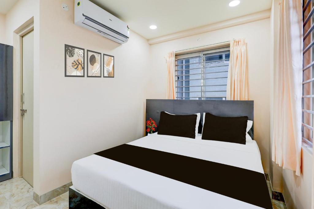 a bedroom with a white and black bed and a window at Townhouse MVP Sector With Kailasagiri Hill View in Visakhapatnam