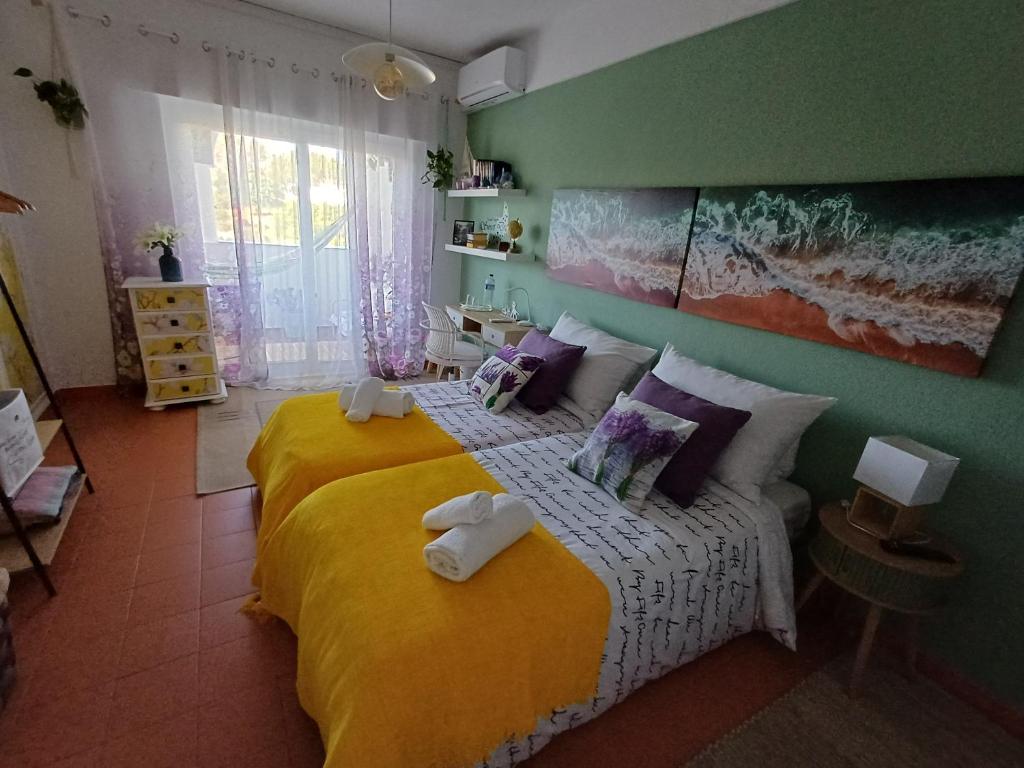 a bedroom with a large bed with a yellow blanket at Quarto Casa na Praia in Porches