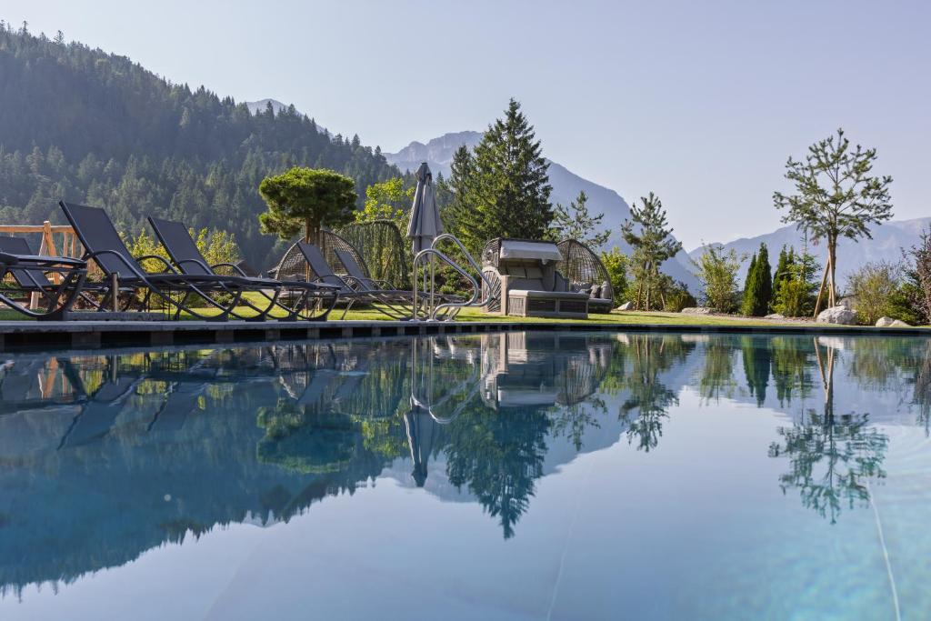 a swimming pool with chairs and mountains in the background at Boutiquehotel Acherl in Achenkirch