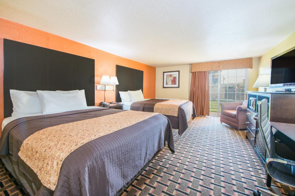 a hotel room with two beds and a television at Days Inn by Wyndham Joplin in Joplin