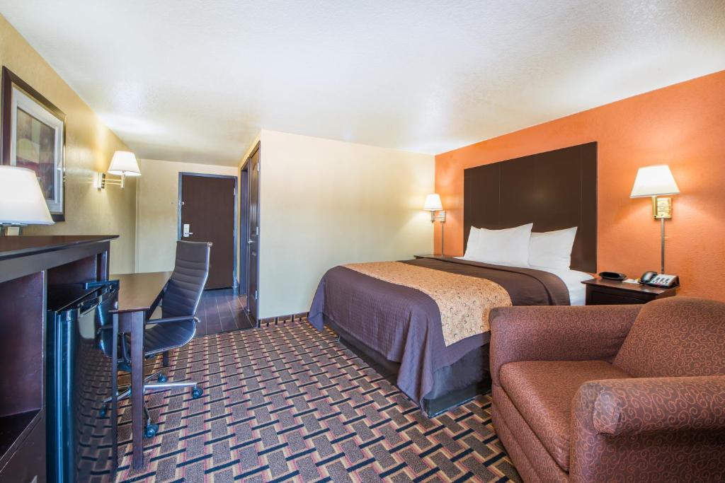a hotel room with a bed and a chair at Days Inn by Wyndham Joplin in Joplin