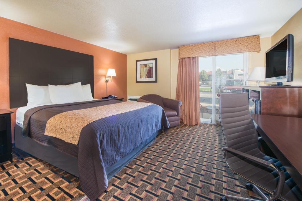 a hotel room with a bed and a flat screen tv at Days Inn by Wyndham Joplin in Joplin