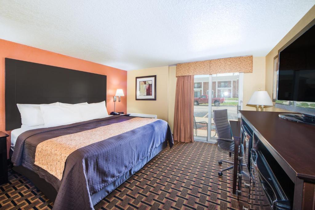 a hotel room with a bed and a desk and a television at Days Inn by Wyndham Joplin in Joplin