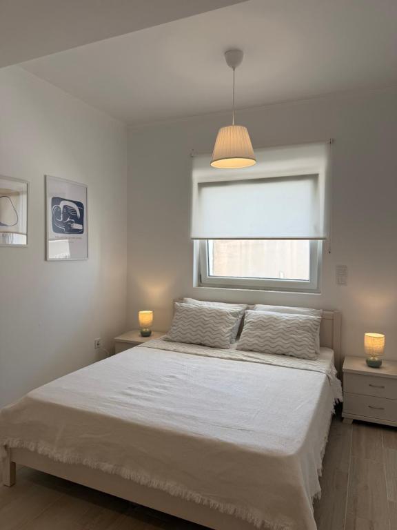 a bedroom with a white bed and a window at Maison Soleil II in Kastro Kyllini