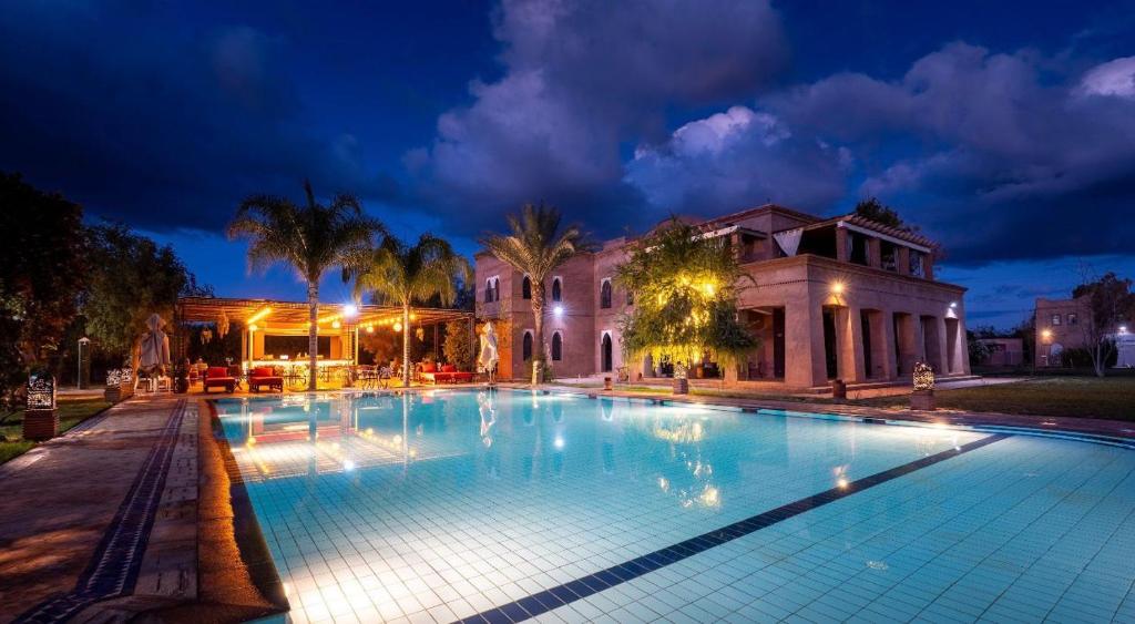 a large swimming pool in front of a building at night at Villa Thaifa & SPA in Marrakesh