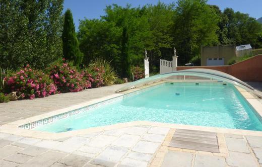 a large swimming pool in a yard with flowers at Gîte de Roques in Serres-sur-Arget