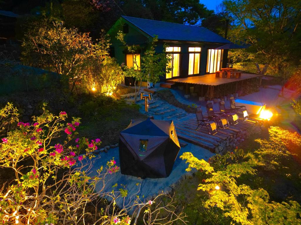 ein Haus mit einem Sonnenschirm im Hof bei Nacht in der Unterkunft HighLand 伊豆大島箱根連峰を望む高級貸切ヴィラサウナ大型ウッドデッキ薪ストーブ完備 in Arashi