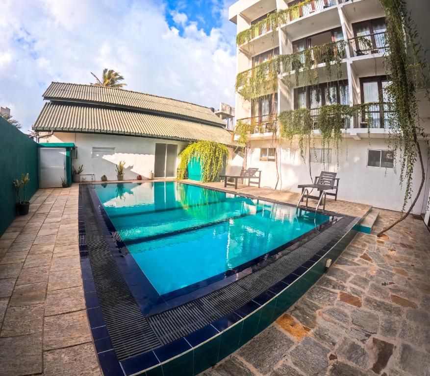 a swimming pool in front of a building at Traveller's Hostel Hikkaduwa in Hikkaduwa