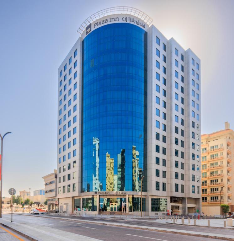 a large blue glass building on a city street at Plaza Inn Hotel in Doha
