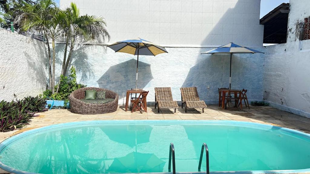 a swimming pool with two umbrellas and a table and chairs at Capitolio Canoa Quebrada in Canoa Quebrada