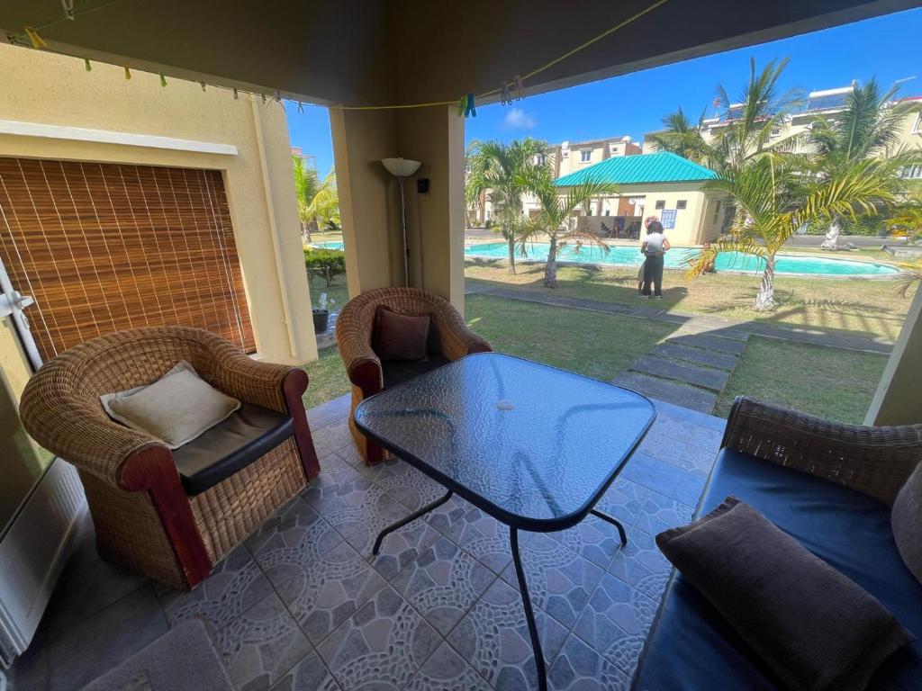 a patio with a glass table and chairs and a pool at Triplex - Suite parentale in Grande Gaube