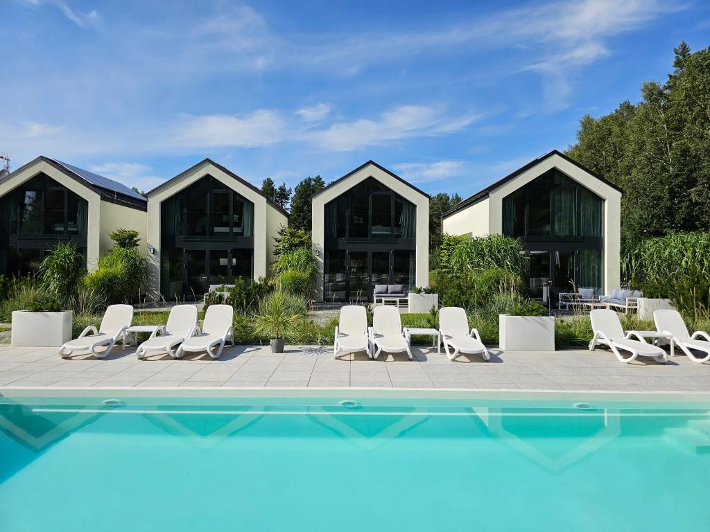 a group of chairs and a pool in front of a building at NOVA ULINIA Forest - dom nad morzem, podgrzewany basen , sauna, balia z jacuzzi, Starlink in Ulinia