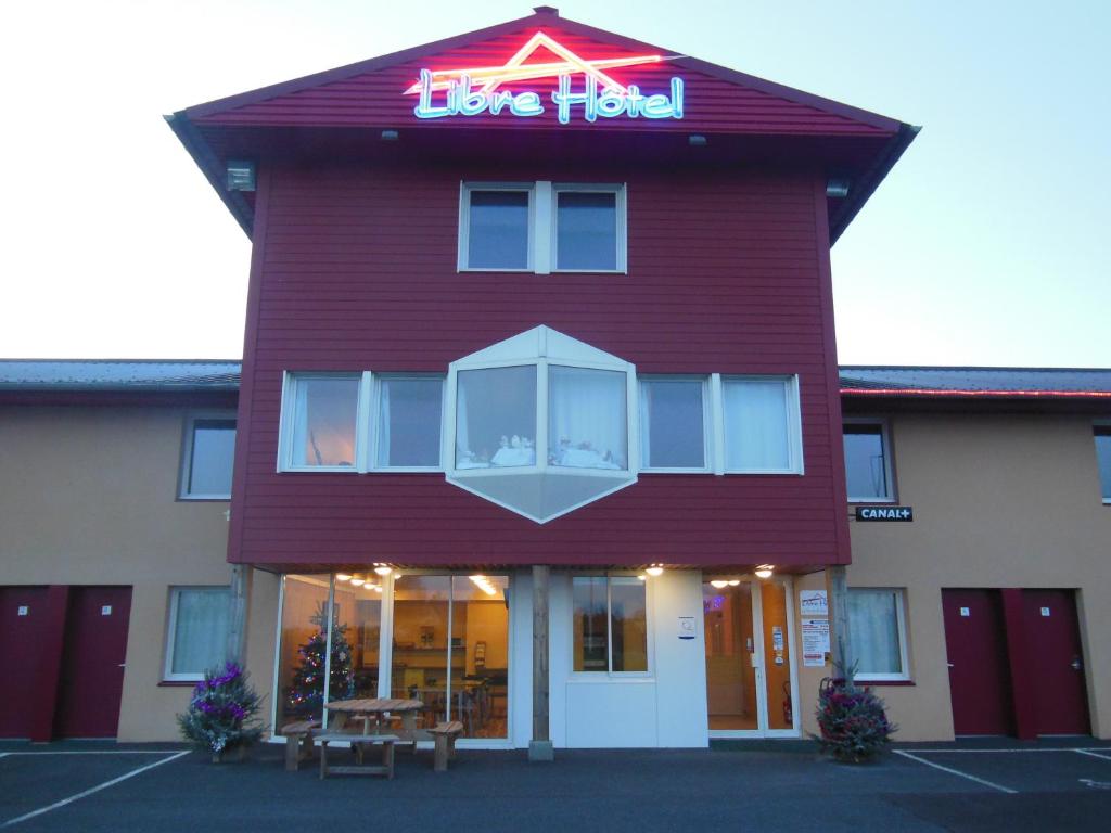 een rood gebouw met een bord waarop staat dat het geteste leven staat bij Libre Hôtel in La Vespière
