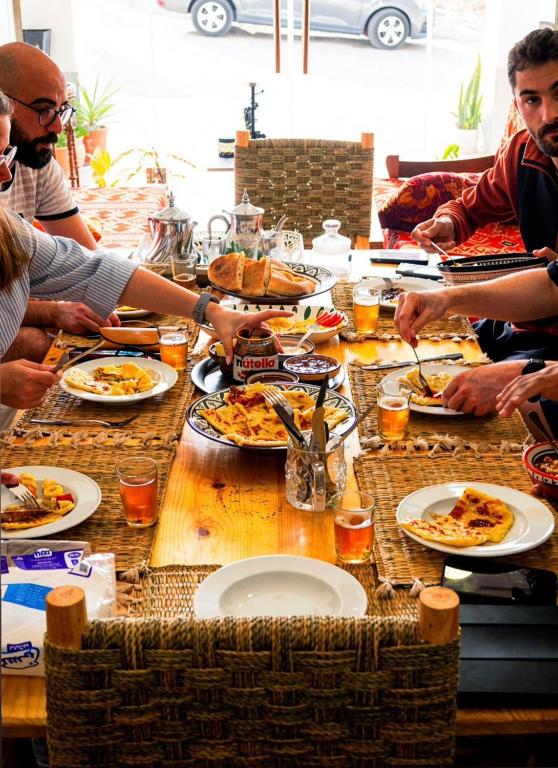 a group of people sitting around a table eating pizza at Imsouane Sea surf Camp in Imsouane