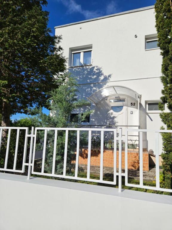 a white fence in front of a house at FAMILLE Apartman in Tapolca
