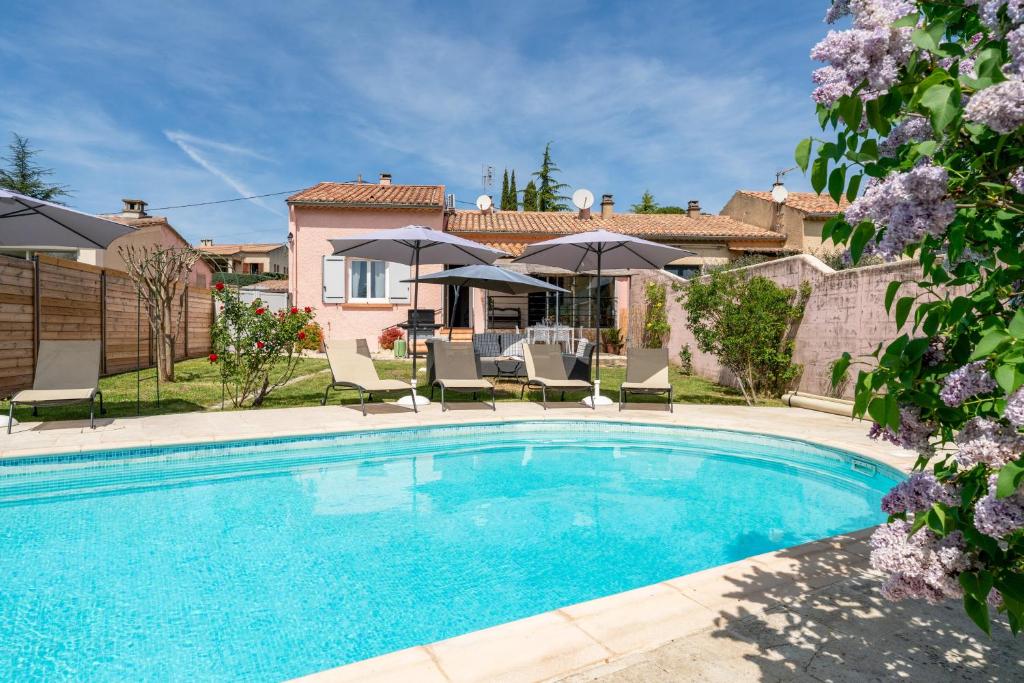 a pool with chairs and umbrellas in front of a house at Maison proche Vaison la Romaine in Saint-Romain-en-Viennois