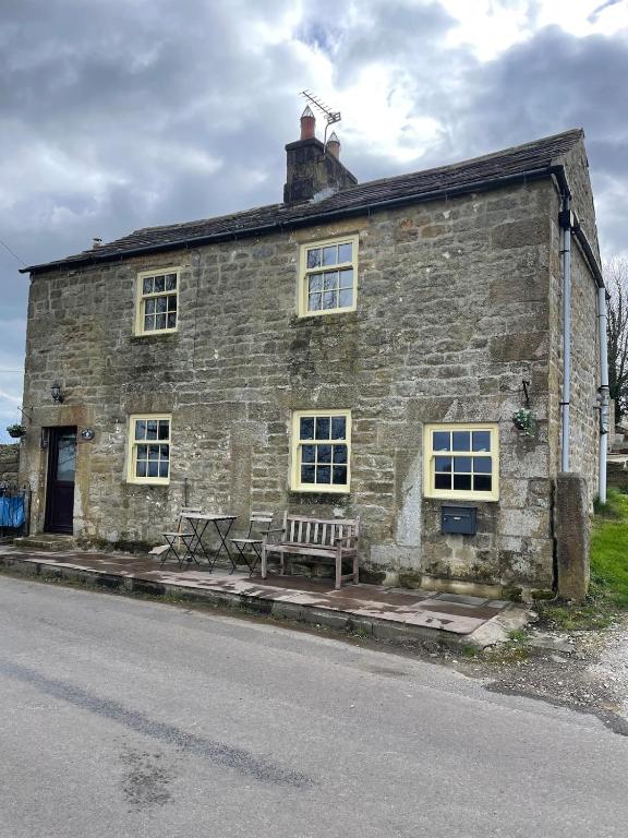 an old stone building with a bench in front of it at Delightful detached 2 bedroom cottage in Grantley