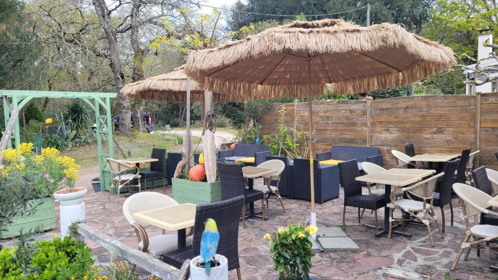 a patio with tables and chairs and a large umbrella at Résidence Fleur des Pins - Gites & Chambres d'Hôtes in Saint-Georges-dʼOléron
