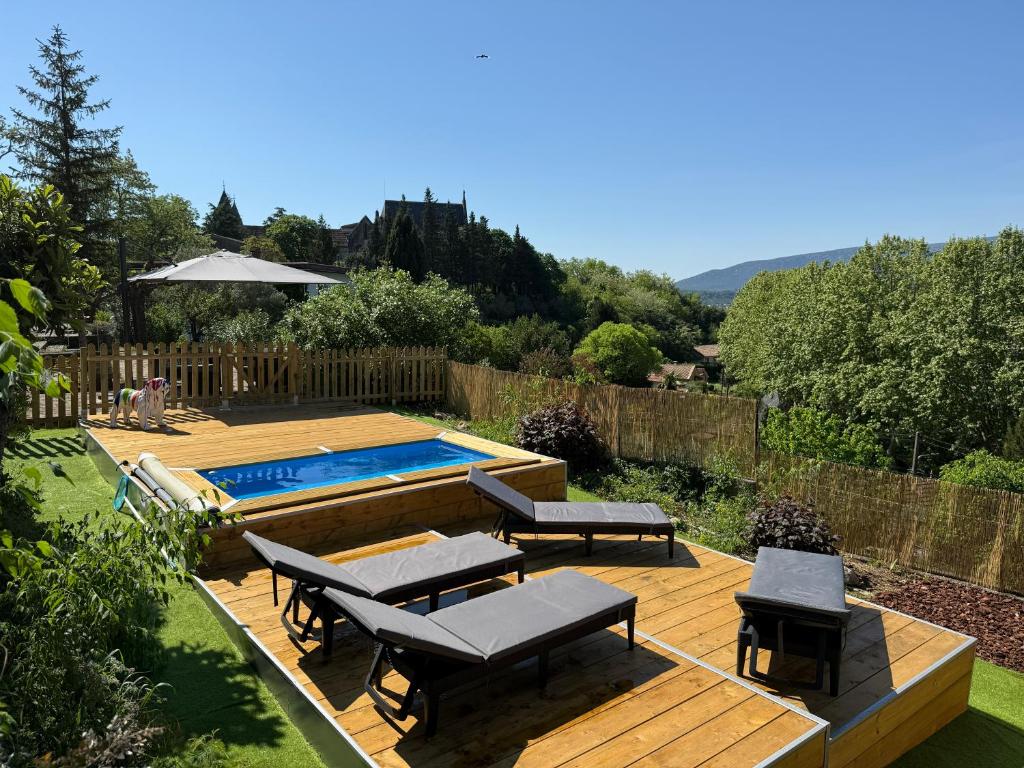 a backyard with a wooden deck and a swimming pool at L'Olivada, villa d'exception in Ganges