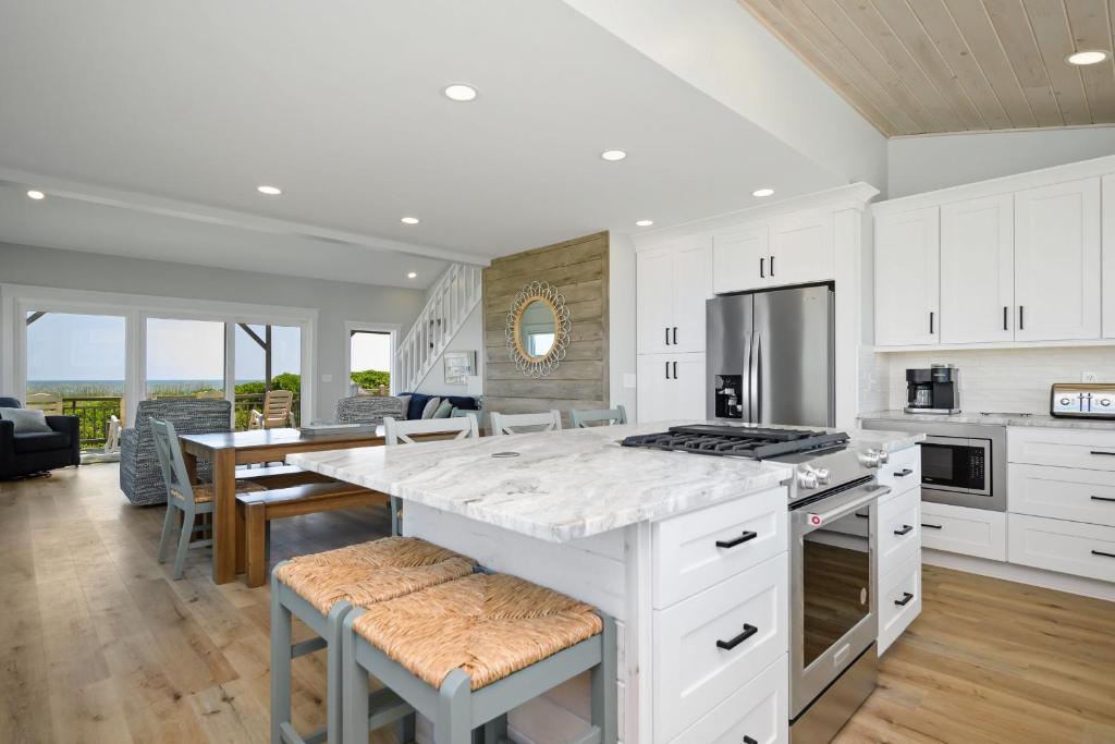 a kitchen with white cabinets and a table with chairs at Beach Buzz by Oak Island Accommodations in Caswell Beach