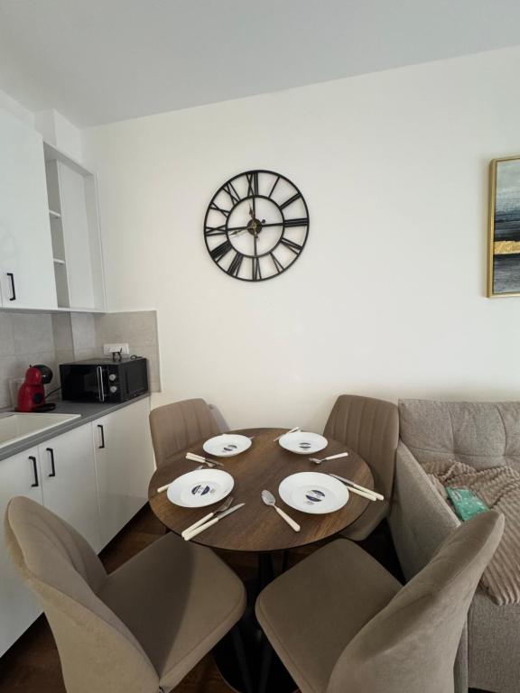 a dining room table with chairs and a clock on the wall at Apartman S in Vrnjačka Banja