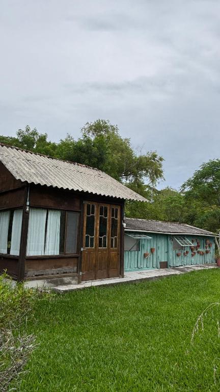 an old barn with a grass field in front of it at Casinha à beira do arroio in Pelotas