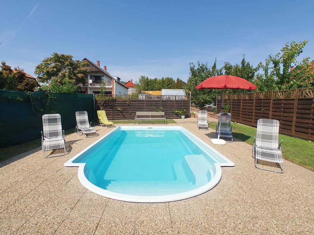 a swimming pool with chairs and a red umbrella at Apartment Anikó Nr 7 in Vonyarcvashegy
