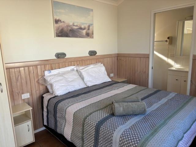 a bedroom with a bed with a blue and white blanket at Longreach Starlight Cabins - Boutique Outback Accommodation in Longreach