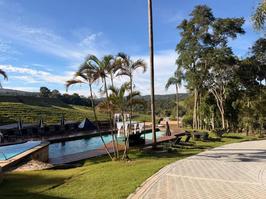 a park with tables and palm trees and a river at Hotel Boutique Vila don Patto in São Roque