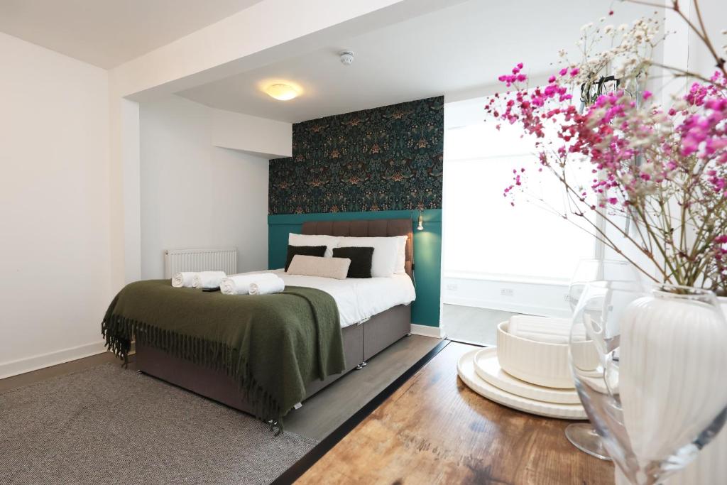 a bedroom with a bed and a vase of flowers at Studio - Kitchen - Parking - Ideal for Contractors in Swansea